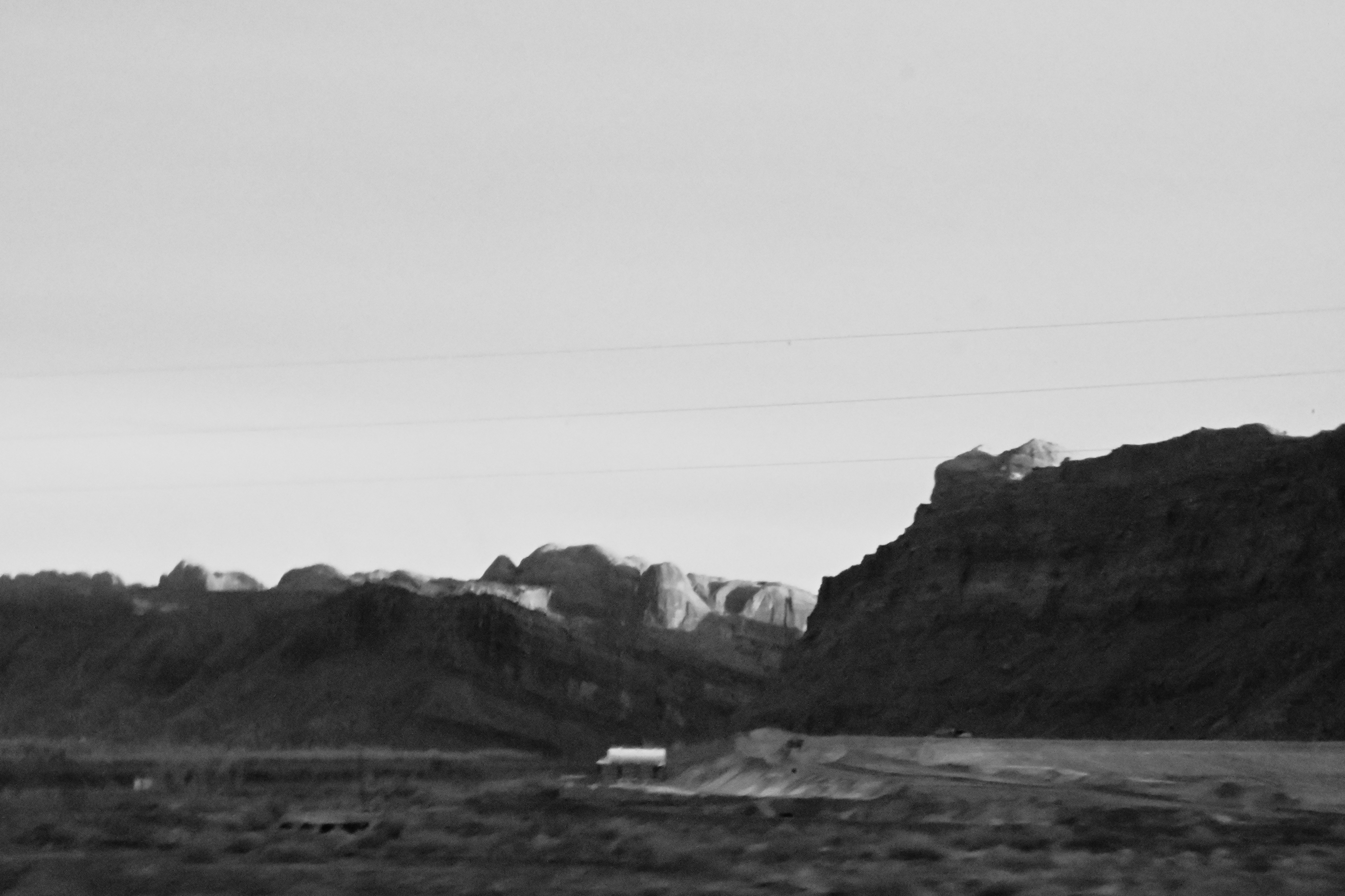 grainy black and white photo of a mountain range and a barn